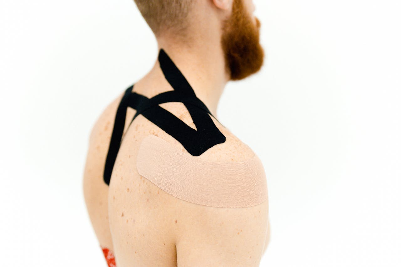 services-01 Close-up view of kinesio tape applied to a man's shoulder for medical treatment.